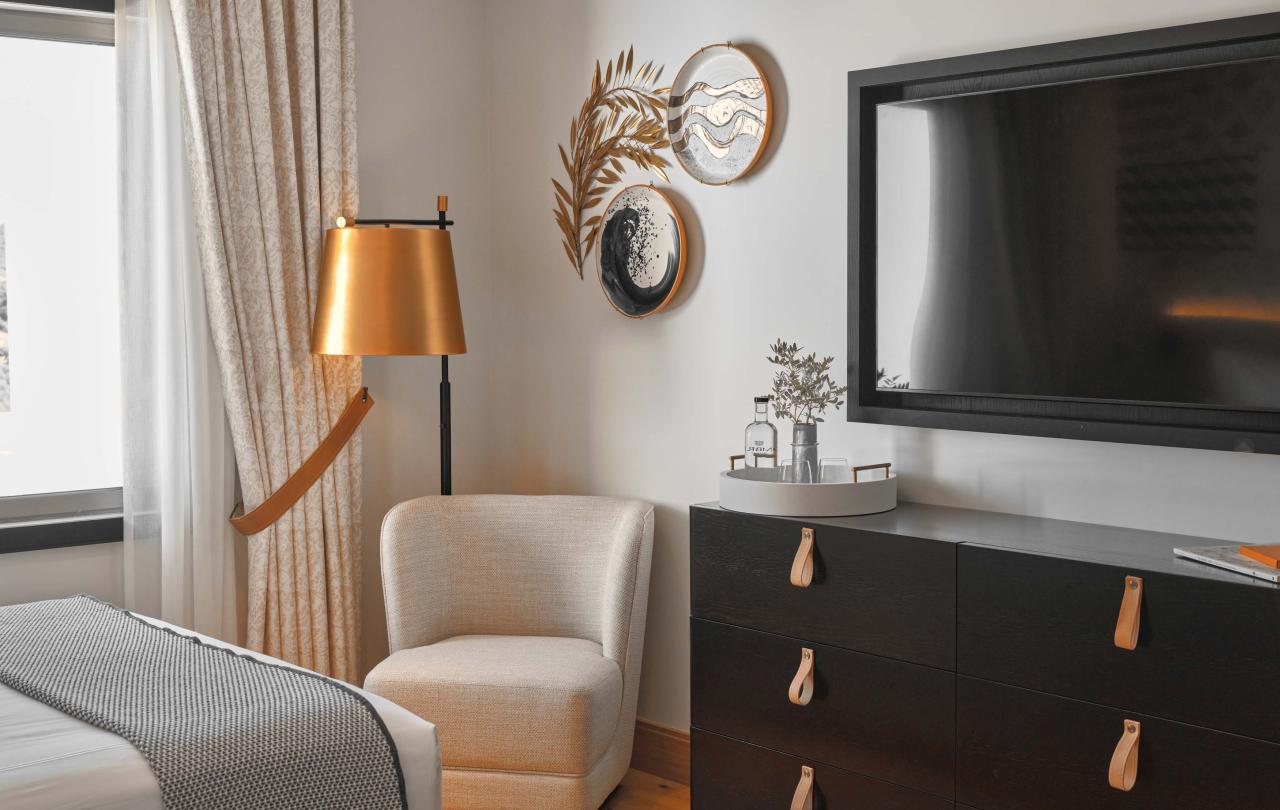 Bedroom with chair and dresser with a tv mounted on the wall
