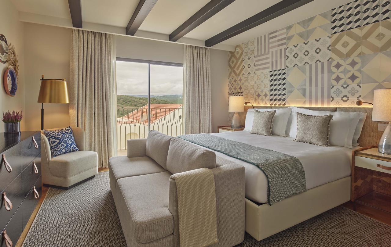 Bedroom with sofa at the foot of the bed and a small chair