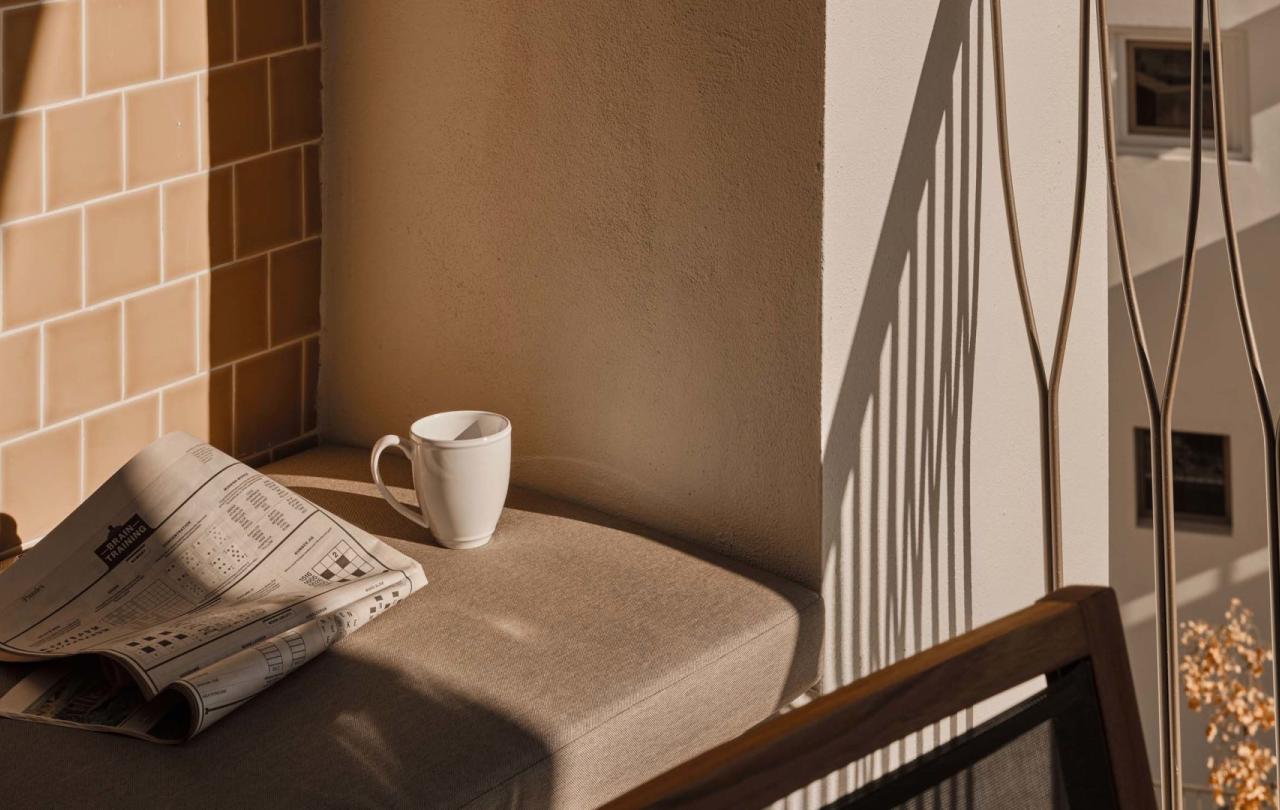 A coffee mug and newspaper resting on a reading nook on an outdoor space of a residence at Viceroy Ombris Algarve