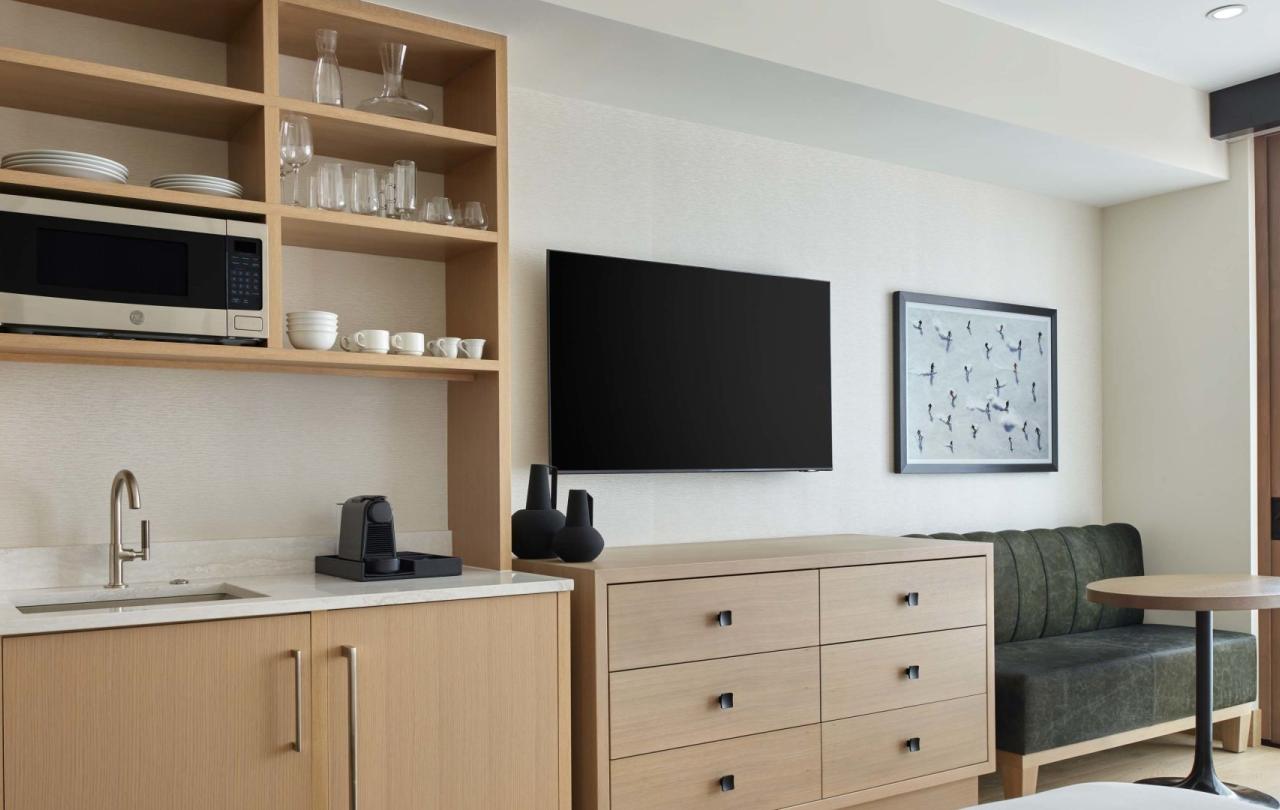 The interior of a Cirque Tower guestroom at Viceroy Snowmass, with a wall mounted TV and cabinet