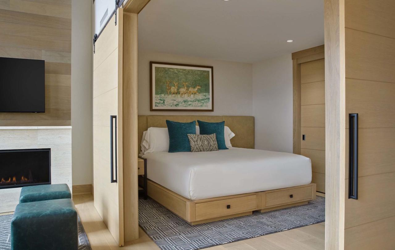 A king bed and the living space with a fireplace in a Cirque Two Bedroom Penthouse Loft at Viceroy Snowmass