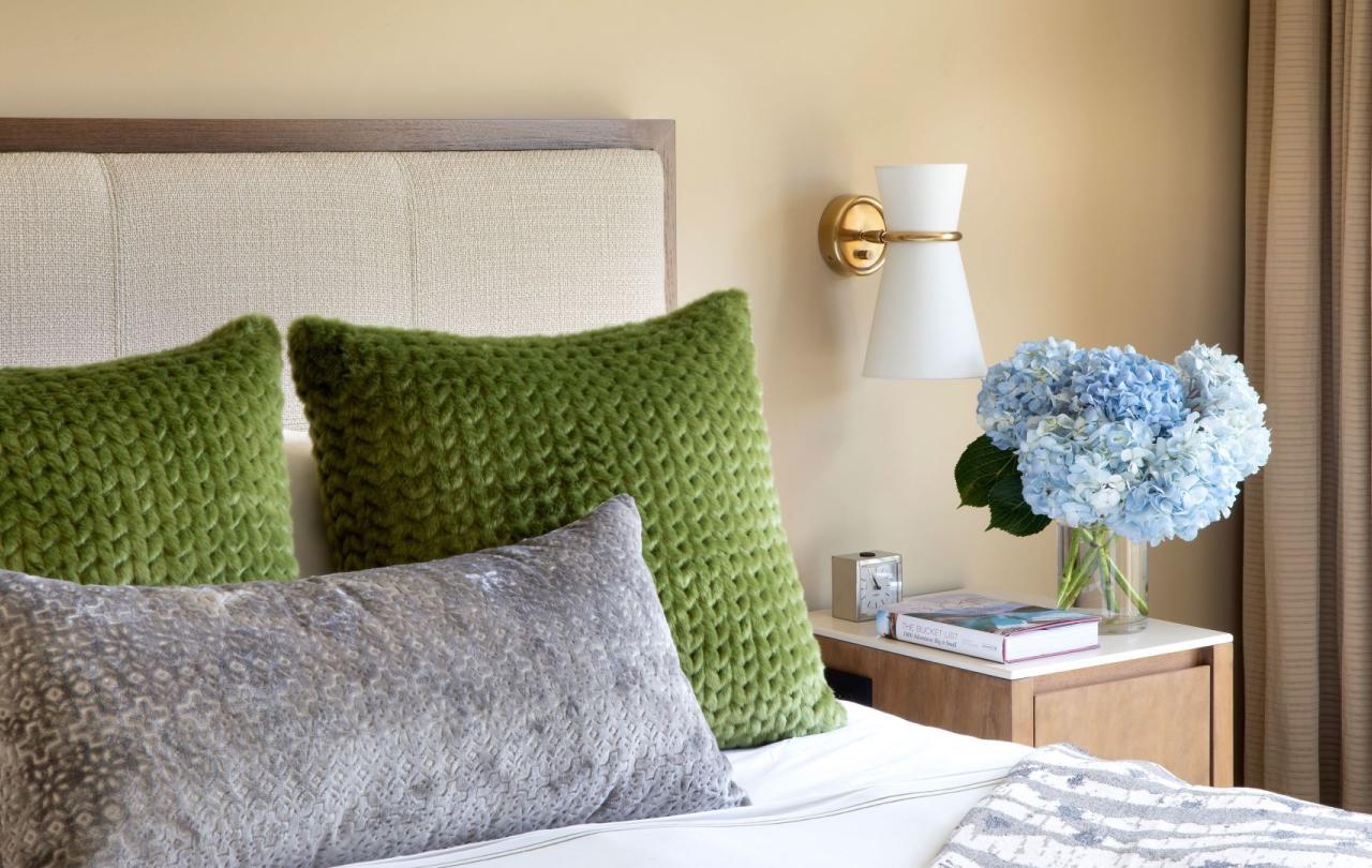 A king bed with green pillows on it and blue flowers on the nightstand in a pinnacle two bedroom residence at Viceroy Snowmass