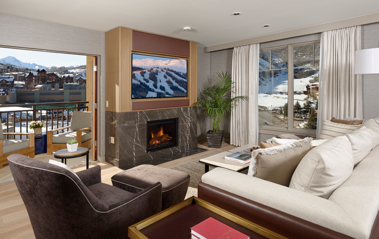 Large living room with a fireplace and two balconies in a Pinnacle Three Bedroom Penthouse at Viceroy Snowmass