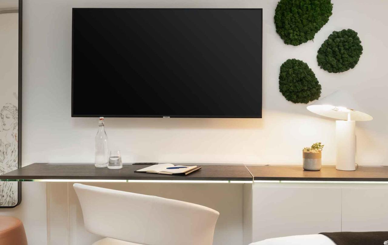 A desk area with a large TV above it in a room at Viceroy Zena Washington