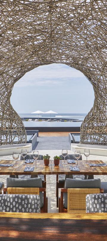 The dining room of Nido restaurant at Viceroy Los Cabos, an outdoor dining terrace under a nest-like dome roof made of woven sticks