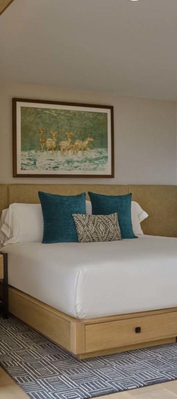 A king bed and the living space with a fireplace in a Cirque Two Bedroom Penthouse Loft at Viceroy Snowmass