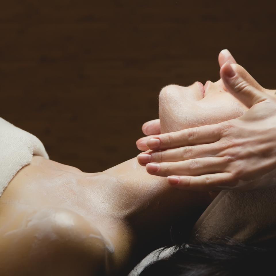 person in a towel getting a facial massage