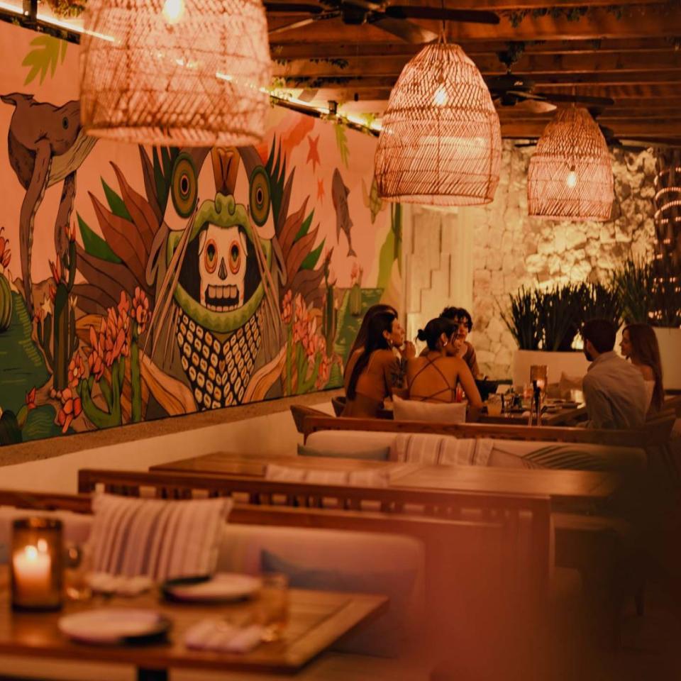Diners eat in a booth at Awacate, next to a large mural