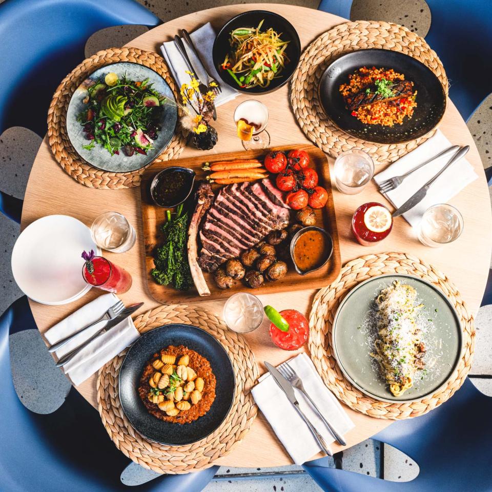 A tomahawk steak, sliced, with accompanying dishes