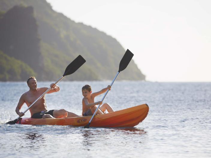 kid and father in orange kayak in middle of ocean