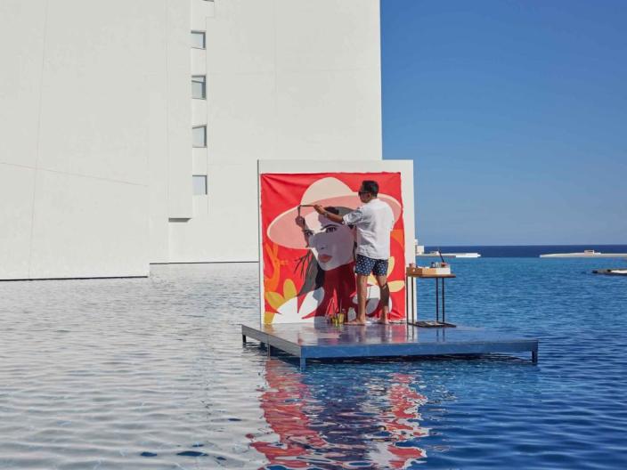 A man paints a portrait on a floating platform in a man-made pool at Viceroy Los Cabos