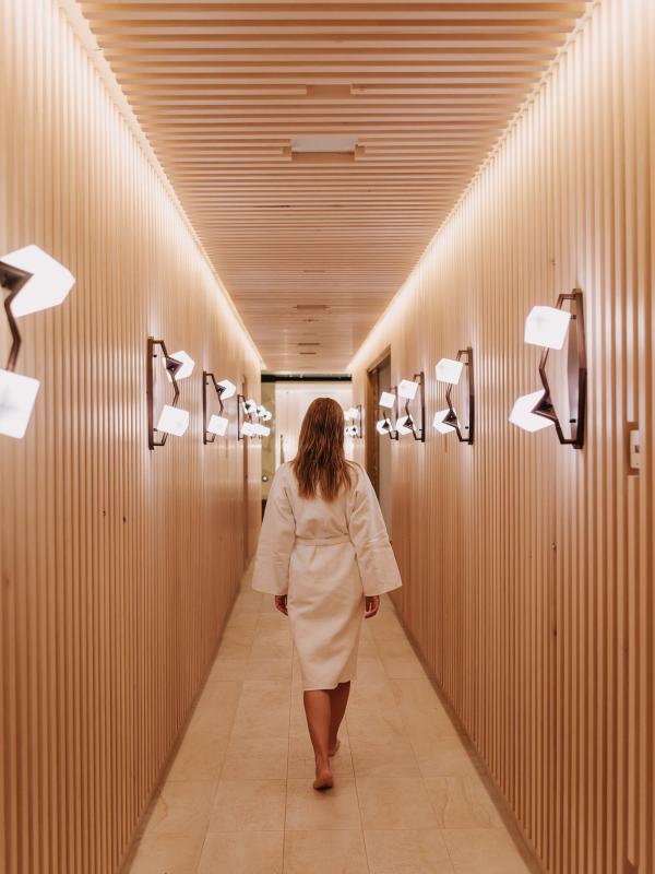 A woman in a bath robe walks along a wood-panelled corridor at the Viceroy Kopaonik Serbia spa