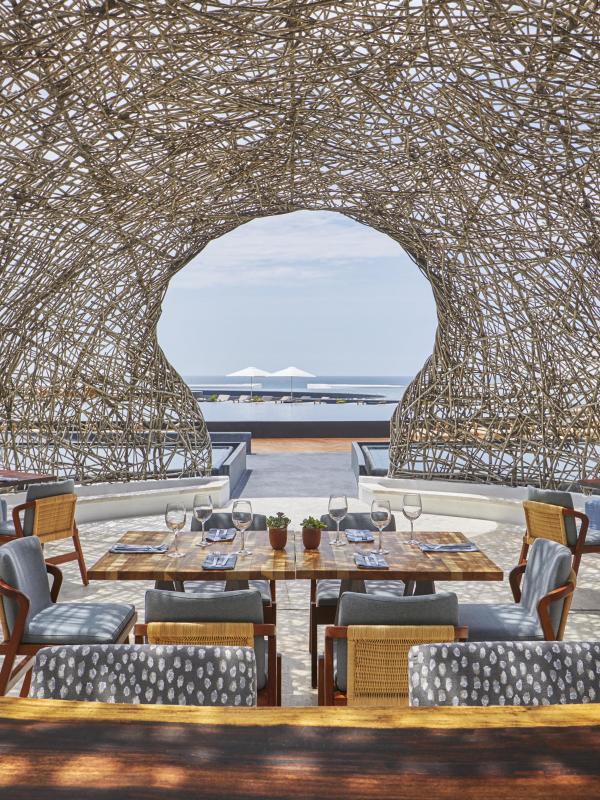 The dining room of Nido restaurant at Viceroy Los Cabos, an outdoor dining terrace under a nest-like dome roof made of woven sticks