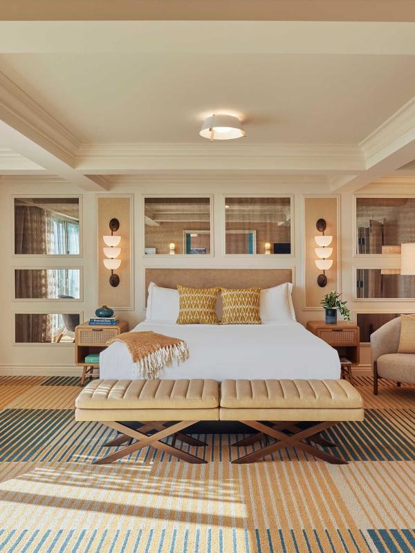 A beautiful large room at Viceroy Santa Monaca with a large bed, two lounge chairs, and a surf board on the wall 